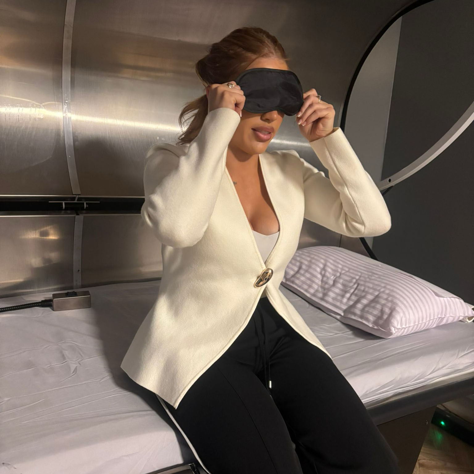 Client preparing for an Ark session, sitting on the chamber bed with an eye mask